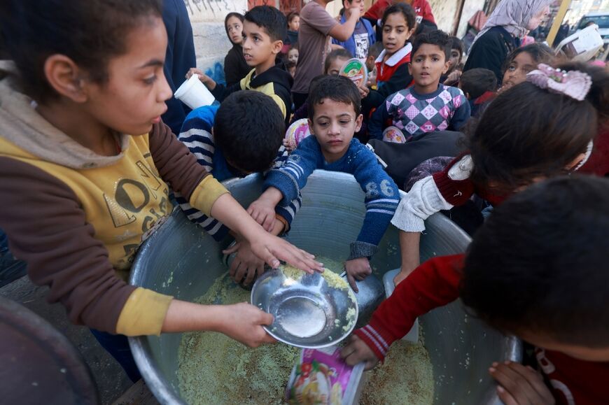 Children collect food at a donation point in Rafah