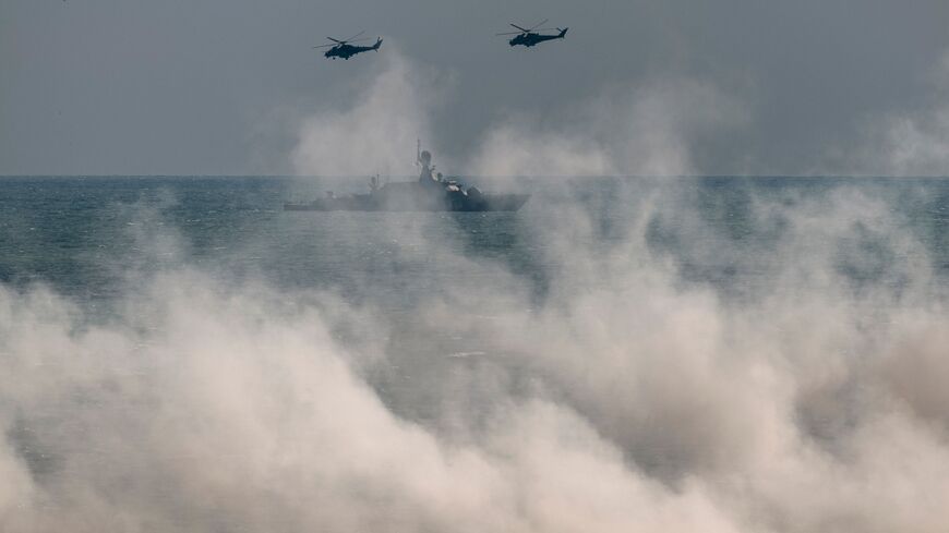 Russian army Mi-24 helicopters fly above a warship at the Turali range on the Caspian Sea coast in the Republic of Dagestan in Southern Russia on September 23, 2020 during the "Caucasus-2020" military drills gathering China, Iran, Pakistan and Myanmar troops, along with ex-Soviet Armenia, Azerbaijan and Belarus. - Up to 250 tanks and around 450 infantry combat vehicles and armoured personnel carriers will take part in the September 21 to 26 land and naval exercises that will involve 80,000 people including 