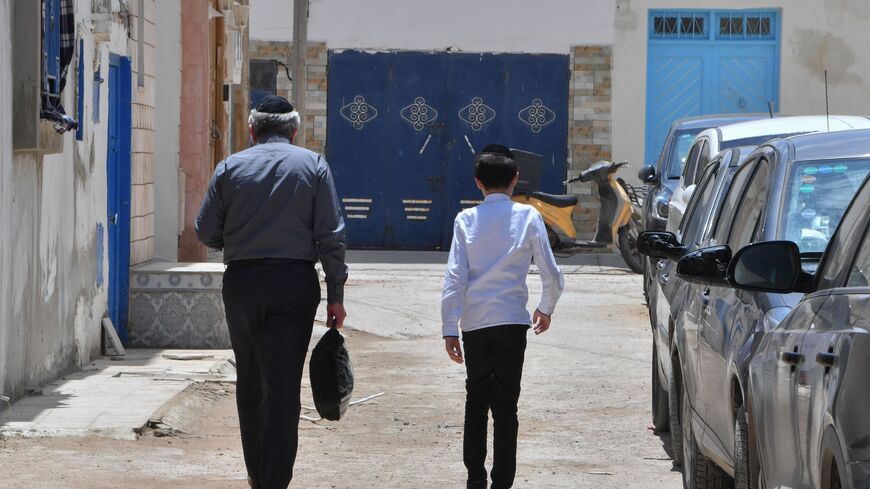 A Jewish man and a child walk through the Hara Kebira, the main Jewish quarter in the resort island of Djerba, near the Ghriba synagogue following a shooting spree by a police officer on the southern Tunisian island on May 10, 2023. Tunisian authorities were investigating the shootings that claimed five lives and sparked mass panic during a Jewish pilgrimage at Africa's oldest synagogue today. (Photo by FETHI BELAID / AFP) (Photo by FETHI BELAID/AFP via Getty Images)